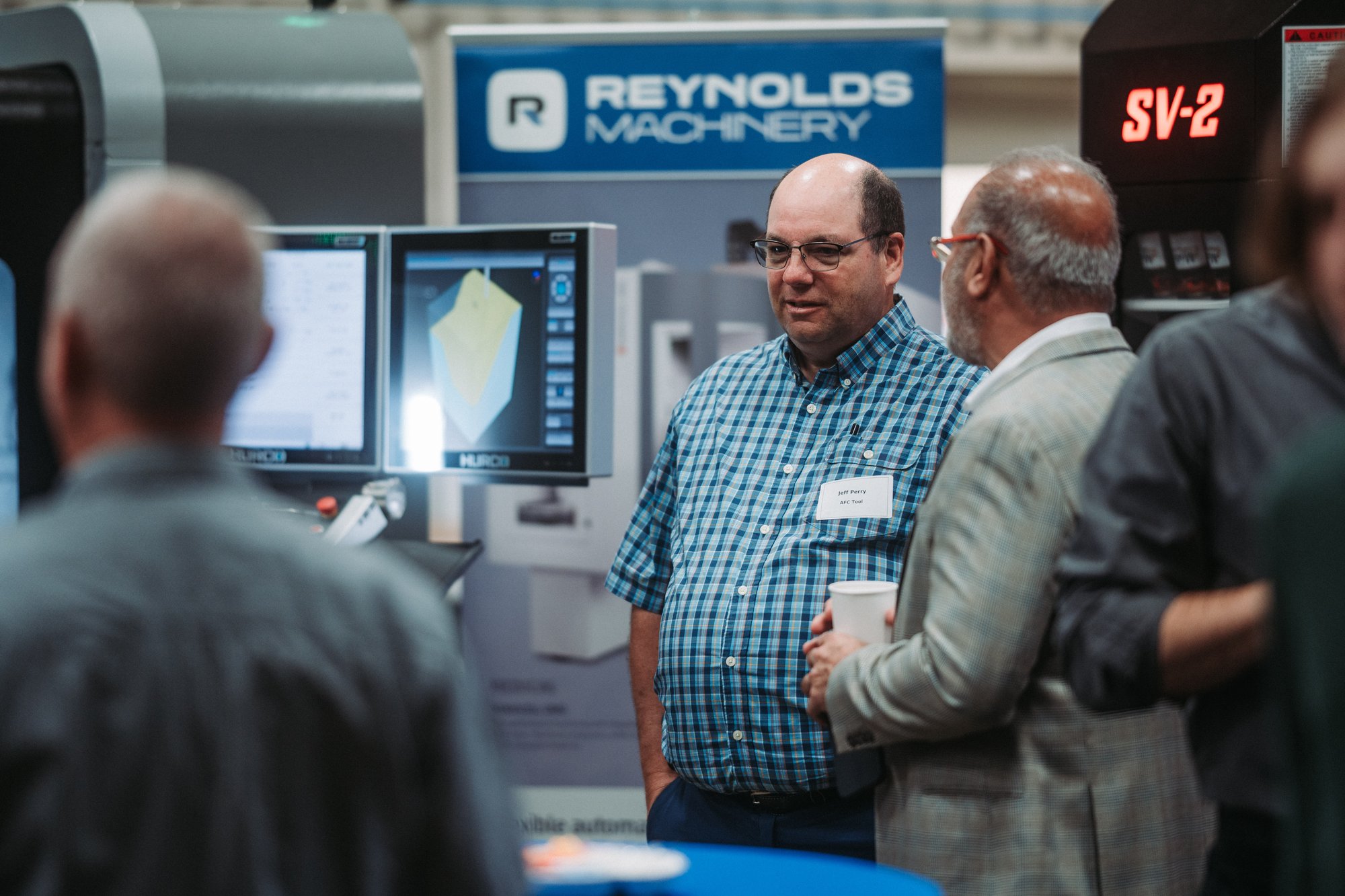 A group of men are talking to each other at the Reynolds Machinery Open House